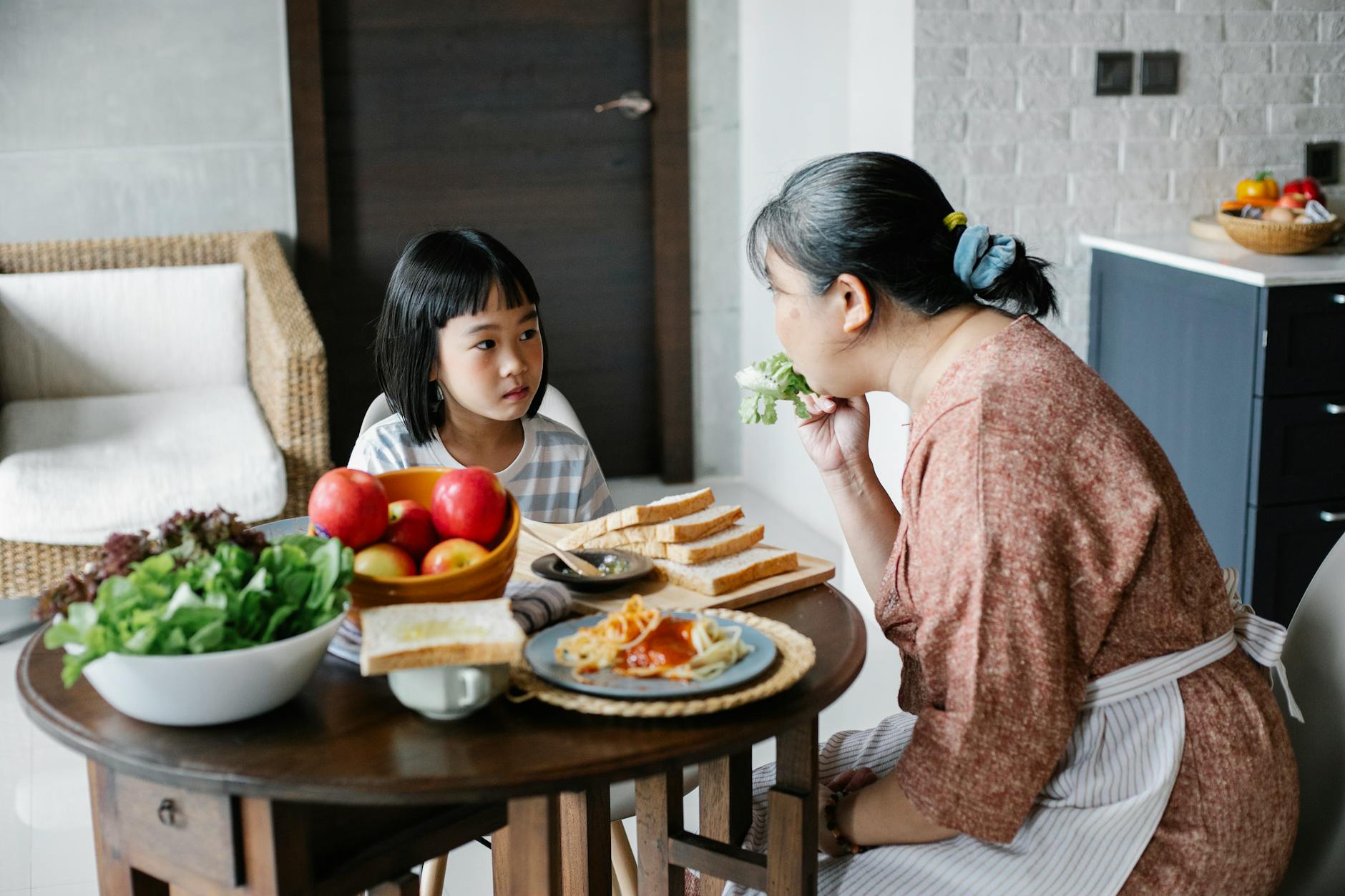 asian mother feeding daughter with healthy food